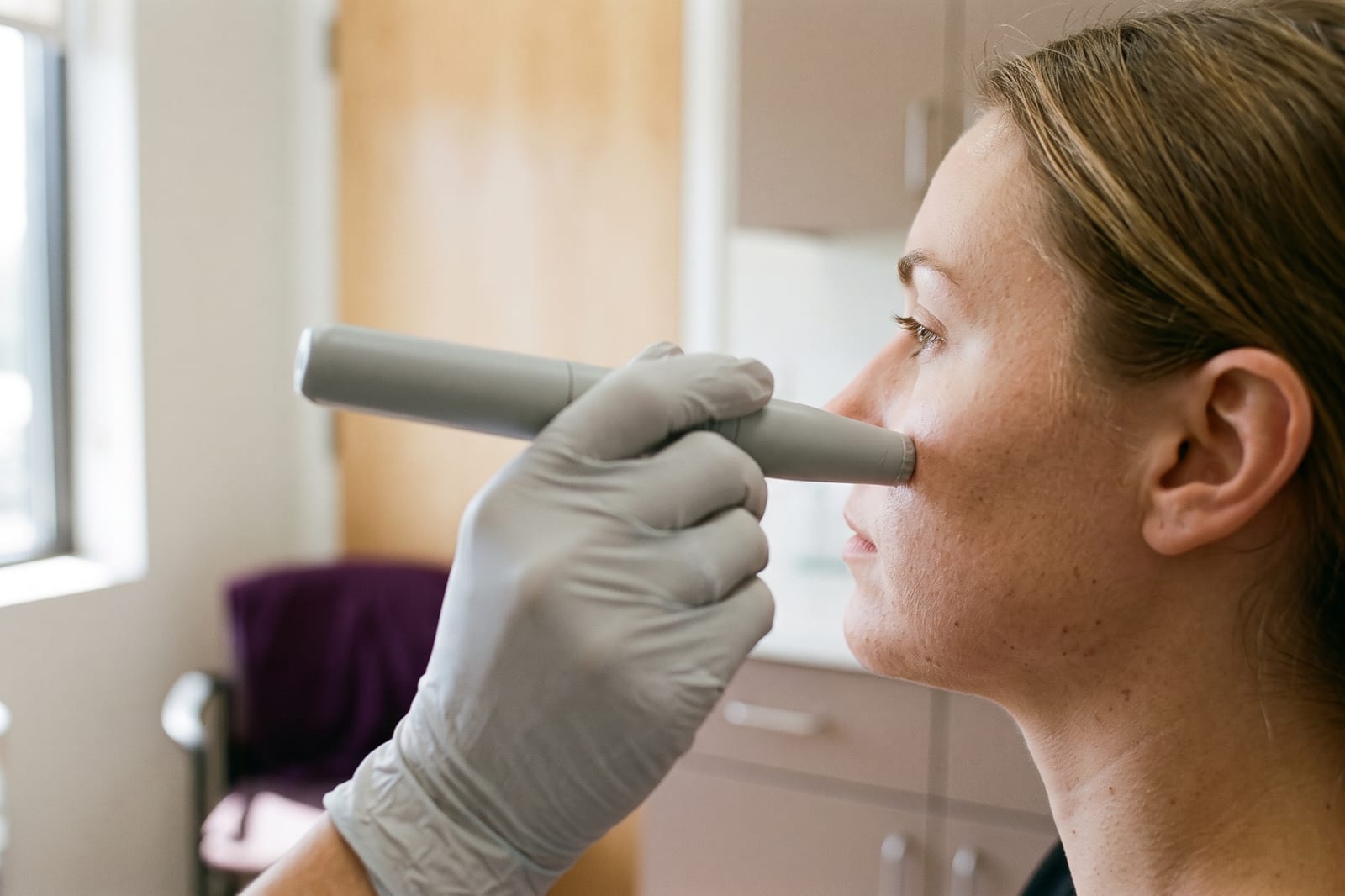 A smooth unbranded handpiece held at a shallow angle against a client’s cheek.